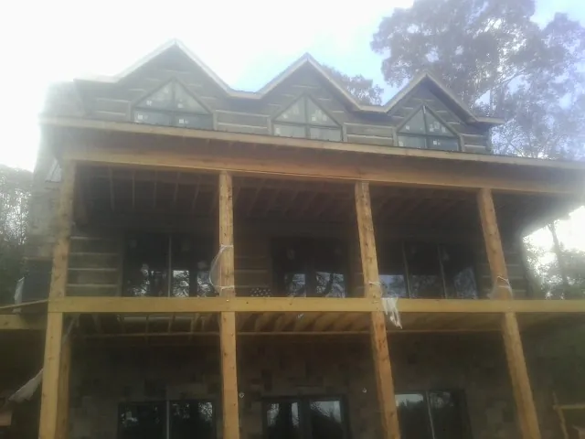 Dormers and porch framing on a large log home under construction — Roof Coating work by our crew in Milton Center
