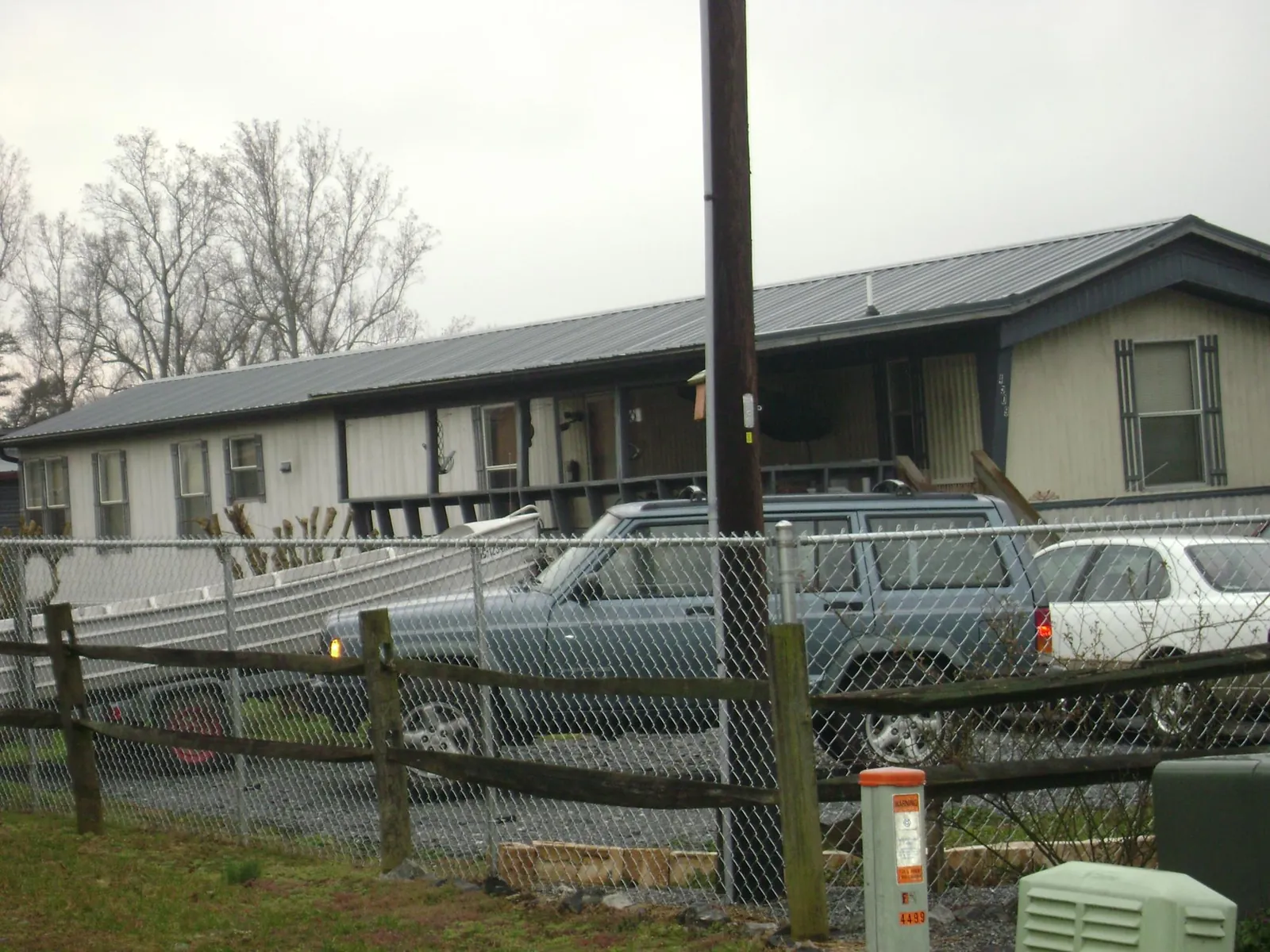 Dark metal roof on a long single story building behind a chain link fence in Milton Center
