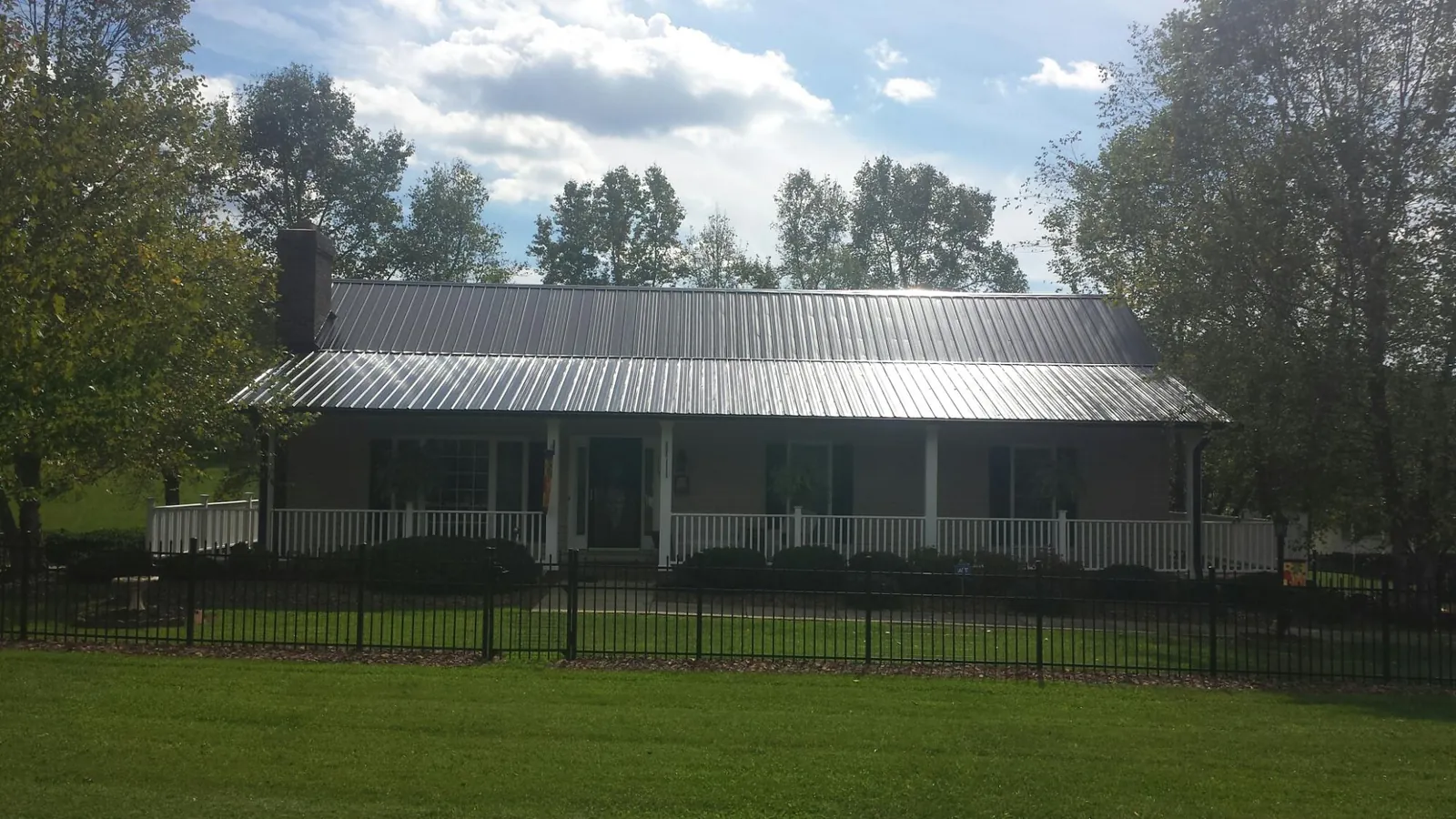 Gray metal roof on a brick ranch with a full width front porch — Gutter Guard Installation work by our crew in Milton Center