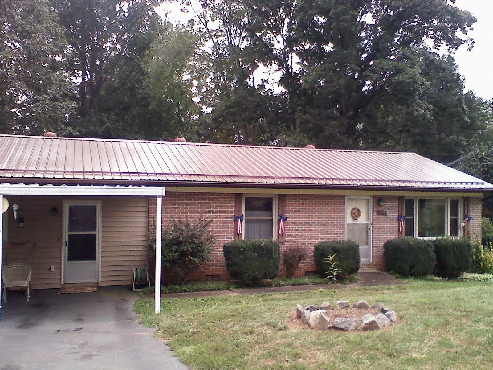 Bronze metal roof and carport on a brick ranch home — Roof Repair work by our crew in Milton Center