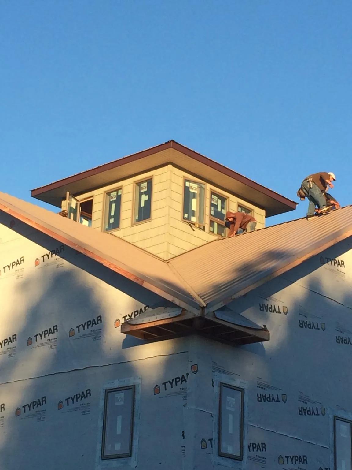 Roofers working around a rooftop cupola on a new metal roof at sunset — Roof Waterproofing in Milton Center by Roofing Brothers
